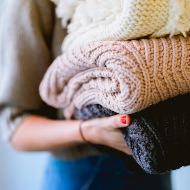 Person trägt gefaltete Strickpullover