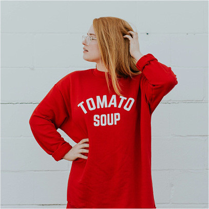 Trendfarben Herbst und Winter 2024 2025 Frau trägt roten Secondhand Pullover mit der Aufschrift Tomato Soup