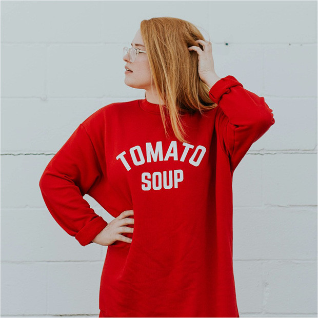 Trendfarben Herbst und Winter 2024 2025 Frau trägt roten Secondhand Pullover mit der Aufschrift Tomato Soup