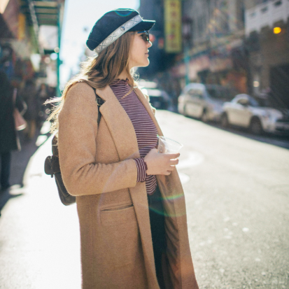 Secondhand Mäntel Frau steht auf der Straße und trägt einen braunen Secondhand Mantel