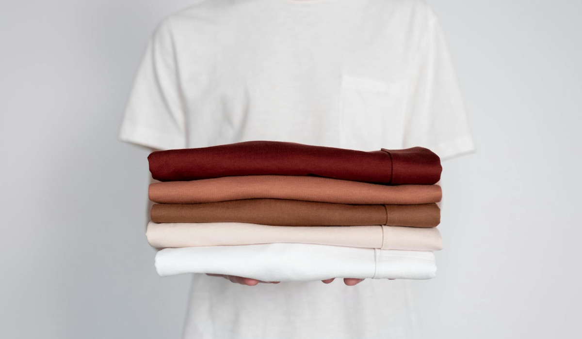 Pflege der Kapsel Garderobe Person hält verschiedene Shirts in den Händen