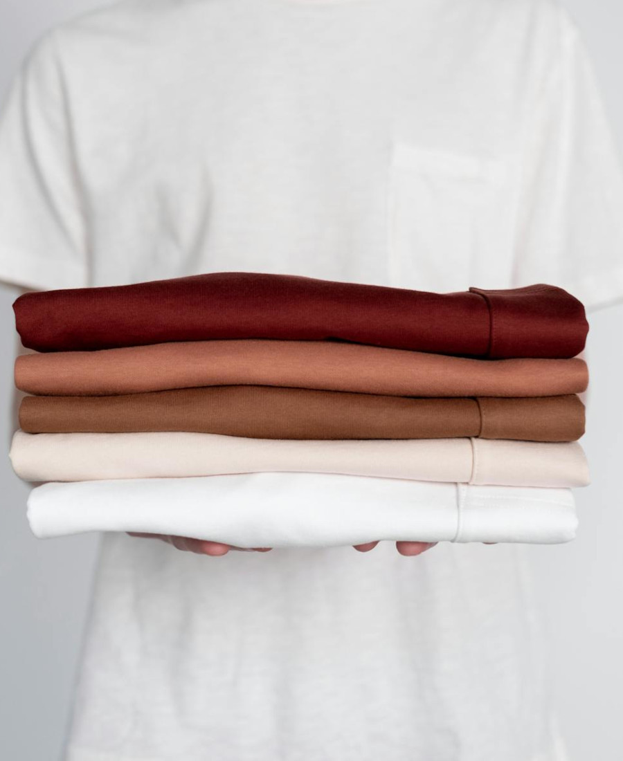 Pflege der Kapsel Garderobe Person hält verschiedene Shirts in den Händen