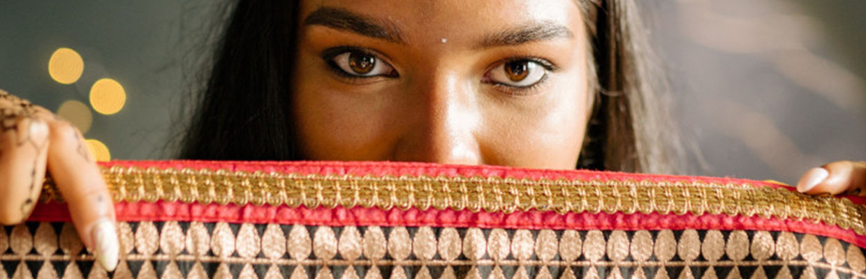 Indische Frau hält Stoff vor ihr Gesicht