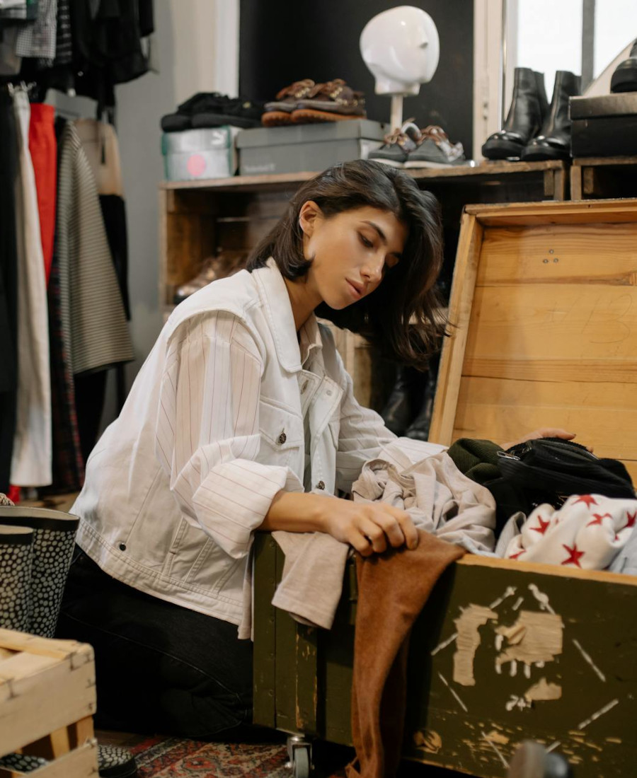 Frau stöbert im Secondhand Laden durch Kiste
