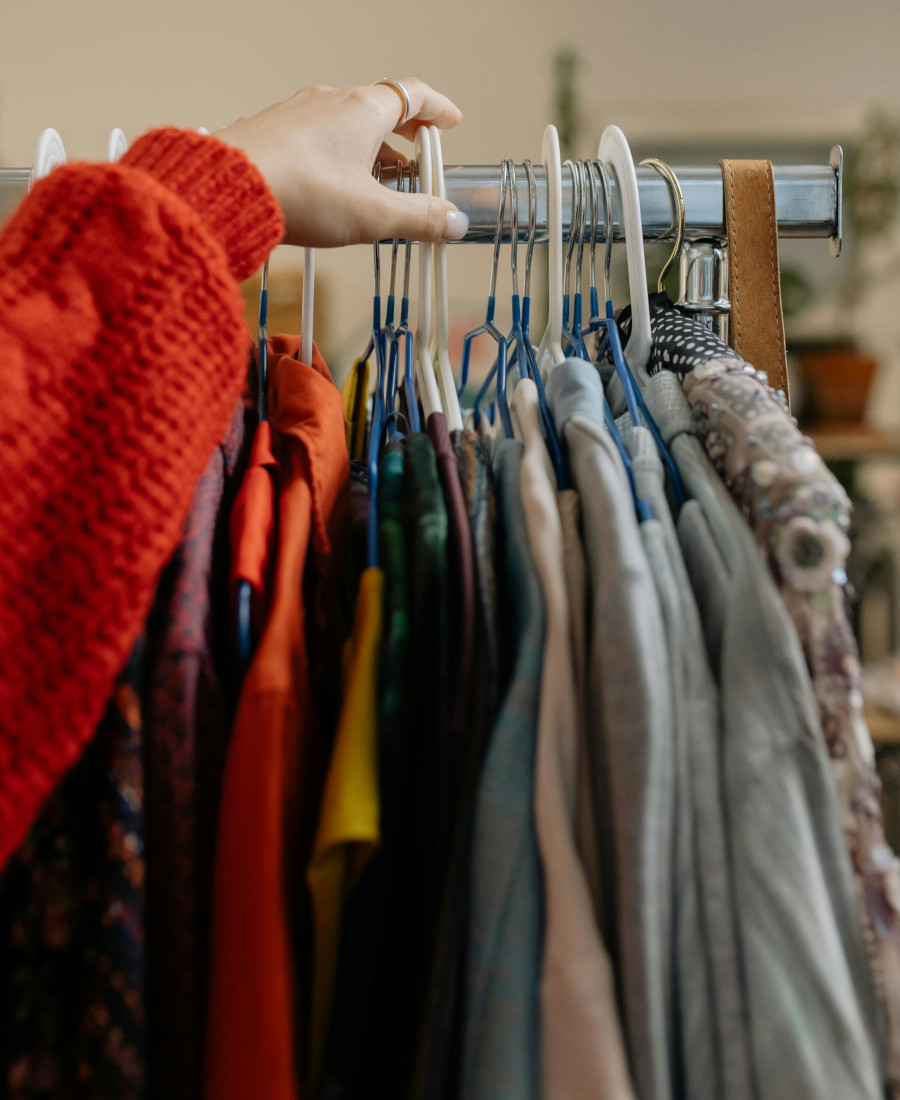 Blogartikel ReSales 7R - Nachhaltiger Modekonsum Hand greift nach Kleidungsstücken auf Kleiderstange