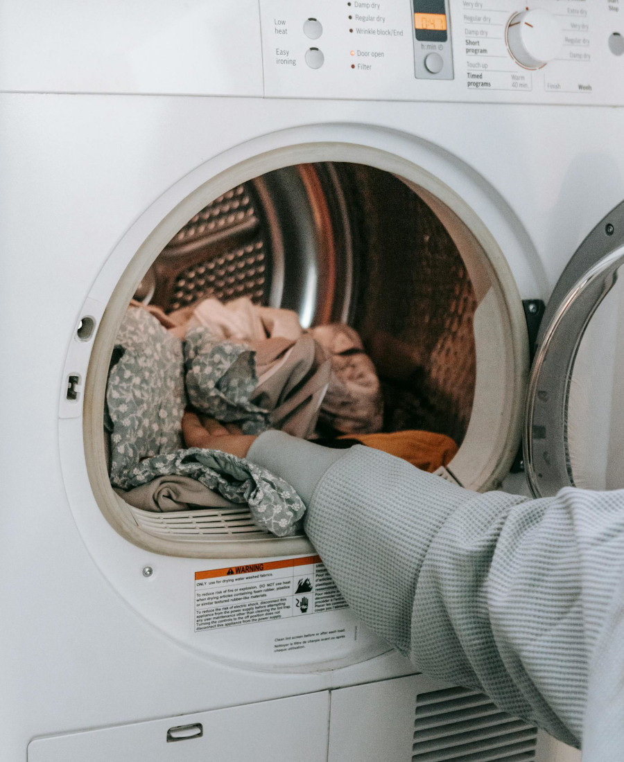 Hand gibt Kleidung in Waschtrommel
